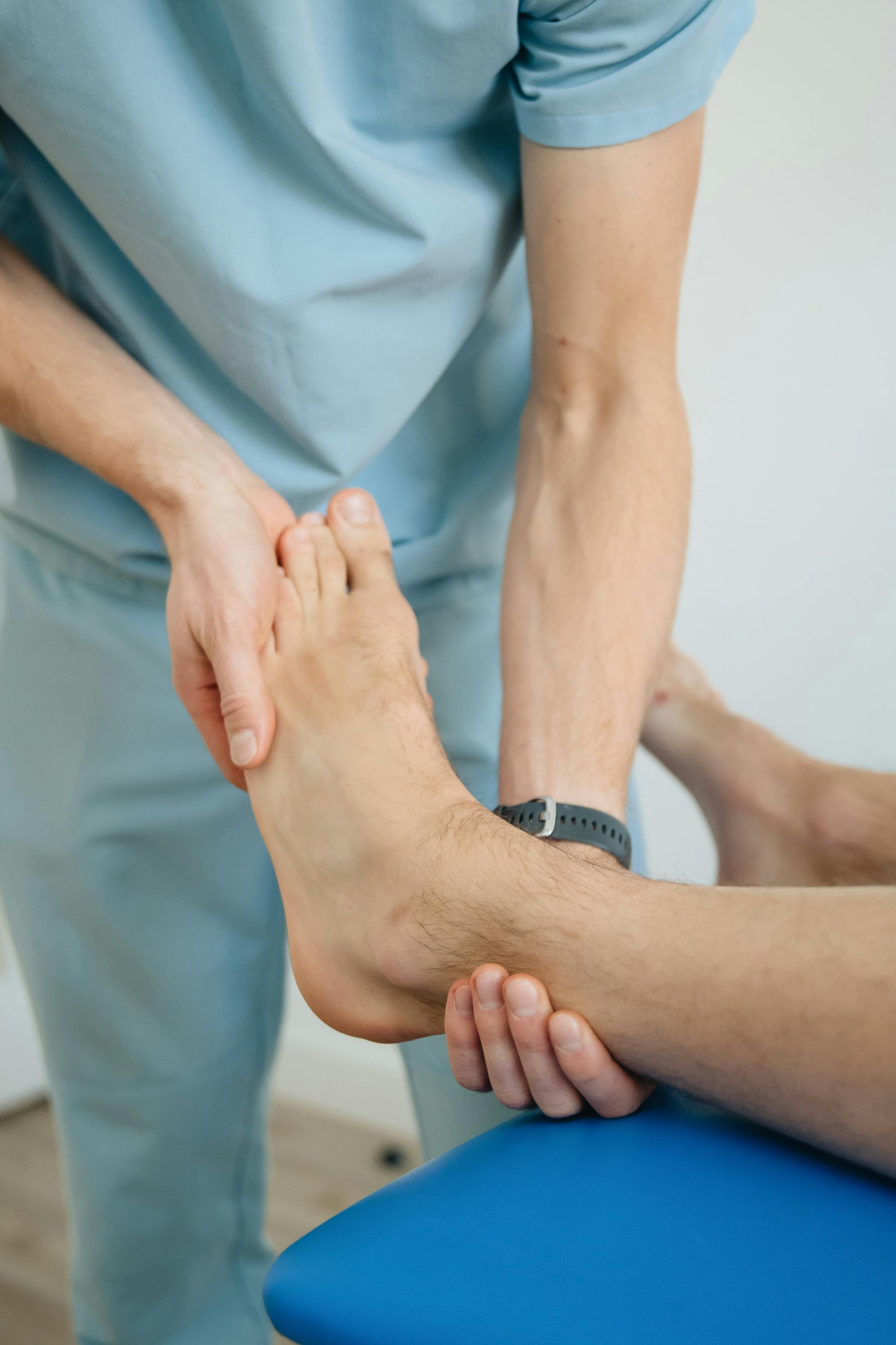 Nahaufnahme eines Physiotherapeuten, der in einer Klinik eine Fußtherapie zur Genesung eines Patienten durchführt.