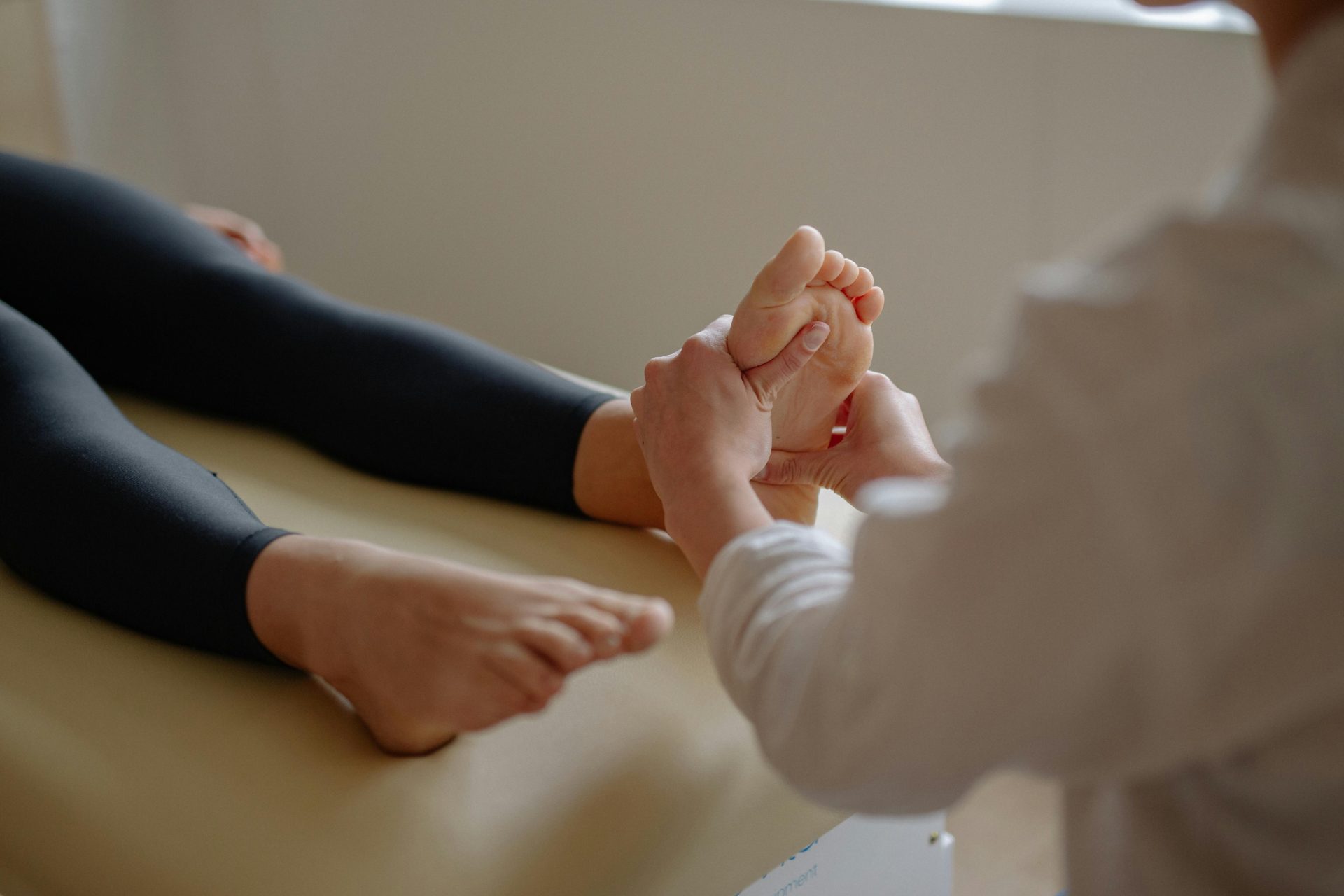 Nahaufnahme einer Fußmassage-Sitzung, bei der ein Therapeut den Fuß eines Kunden behandelt.